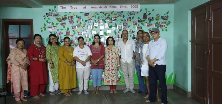 चित्रित रूखको भित्तेचित्रअगाडि उभिएको समूह