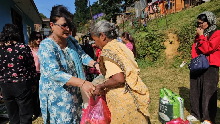 Projects एक वृद्ध महिलालाई राहत झोला दिँदै AAAK सदस्य