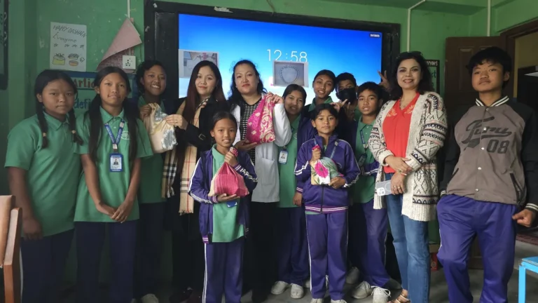 कक्षाको स्क्रिनअगाडि कपडाका झोला समातेर उभिएका विद्यार्थी र तीन महिला अतिथि