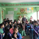 बैजनी ज्याकेट लगाएका विद्यार्थीले भरिएको कक्षा, भित्तासँगै उभिएका AAAK सदस्य