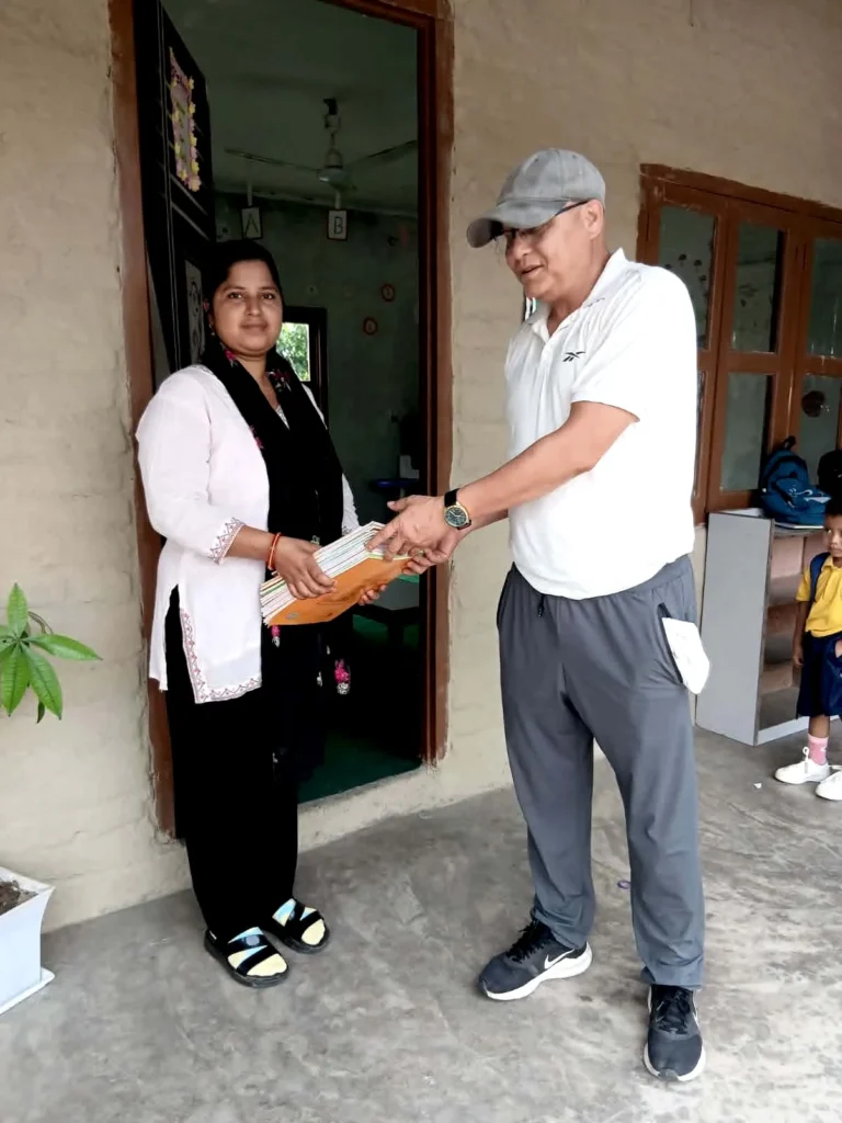 सानो विद्यार्थीले हेरिरहँदा कक्षाकोठाको ढोकामा कापीको चाङ लिँदै शिक्षिका