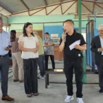 माइकमा बोल्दै गरेका एक व्यक्ति र छेउमा उभिएका अतिथि