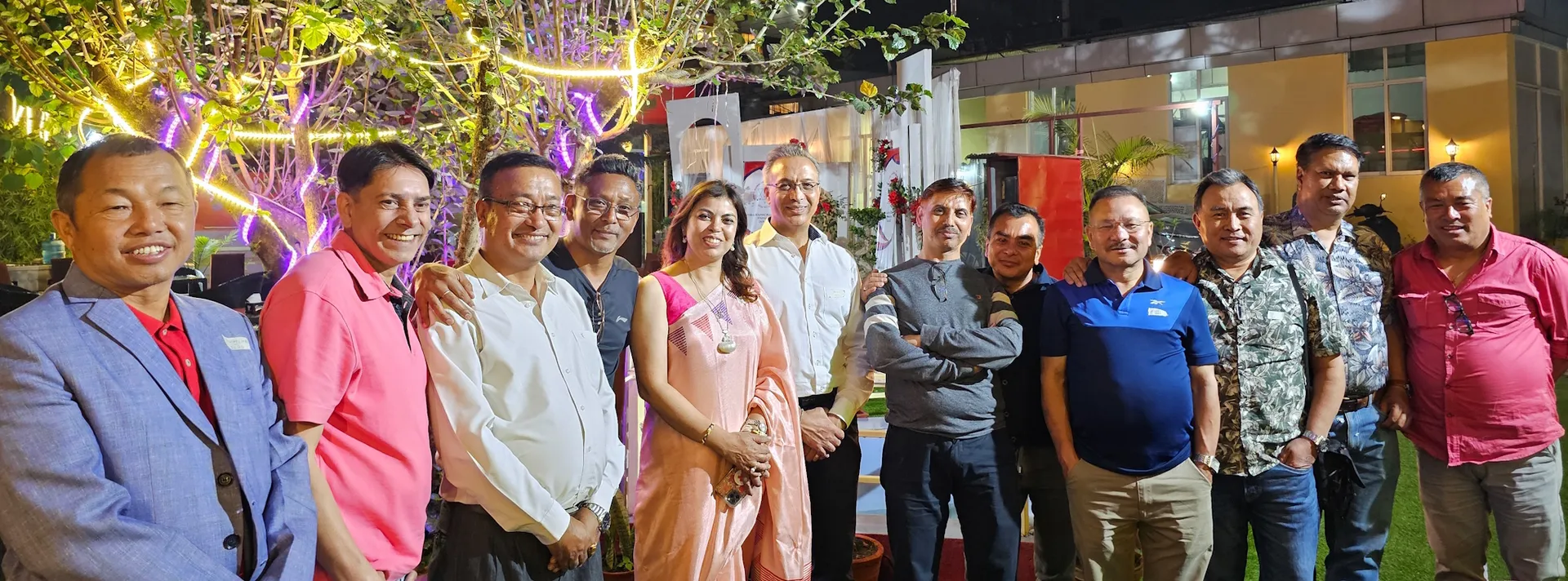 Alumni together in the garden under festive lights at an AAAK evening gathering