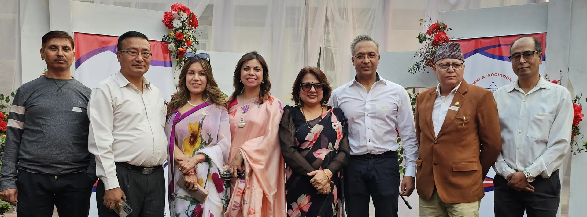 Alumni in front of the AAAK stage with flowers and banners