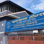 सुनगाभा होम्सको ठूलो निलो साइनबोर्डसहितको गेटपछाडि निलो इँटाको भवन