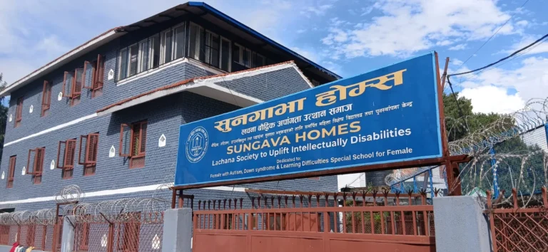 सुनगाभा होम्सको ठूलो निलो साइनबोर्डसहितको गेटपछाडि निलो इँटाको भवन